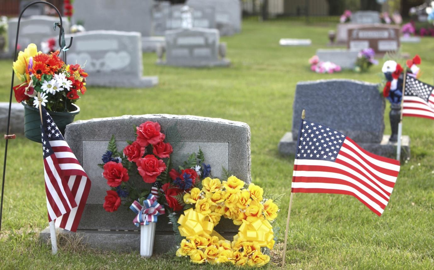Memorial Day flags and flowers placed near cemetery headstones